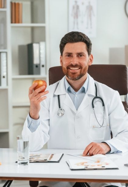 Holding an apple. Doctor in formal clothes is working in the cabinet Holding an apple. Doctor in formal clothes is working in the cabinet.